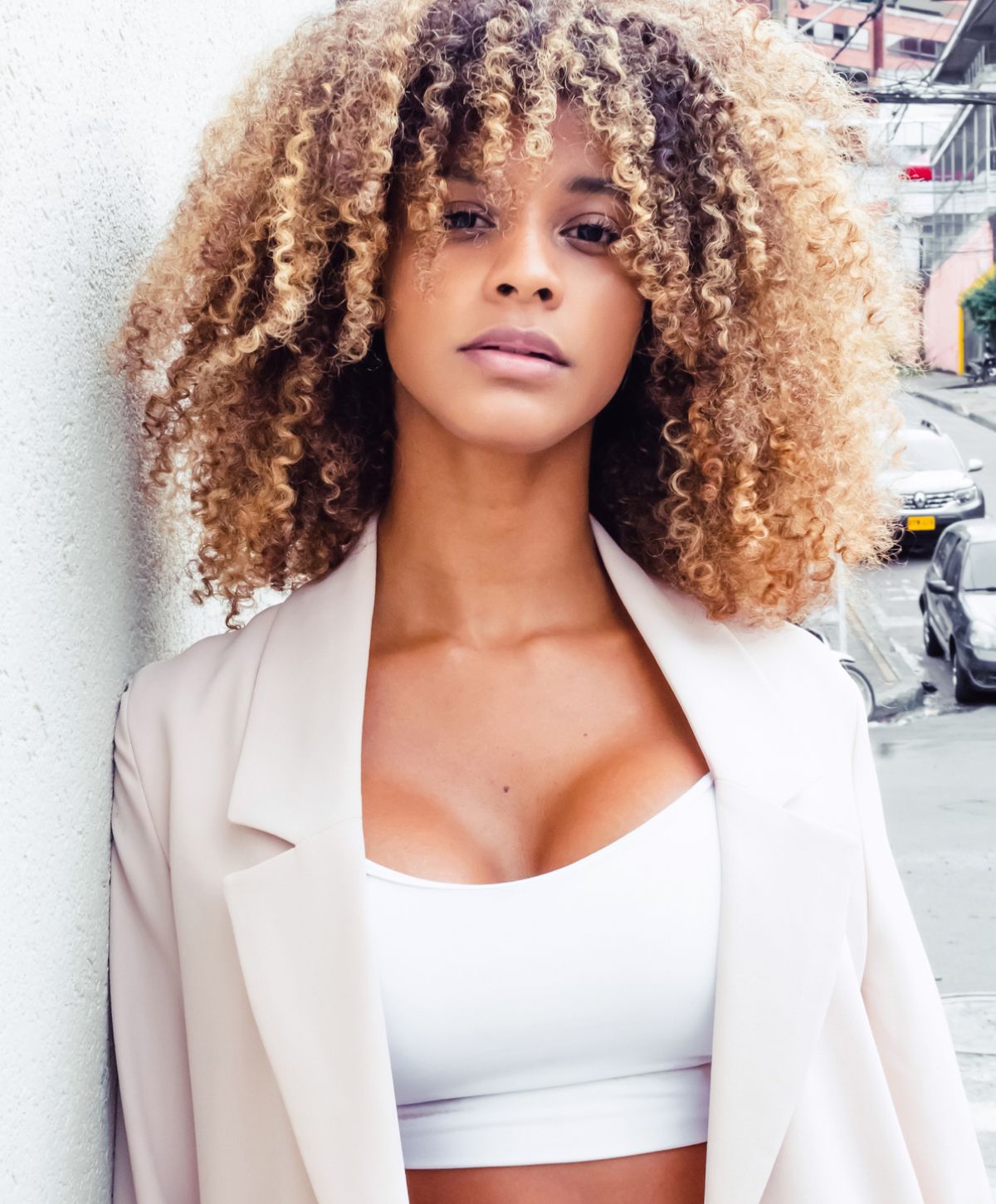 Woman with curly hair wearing a stylish outfit.