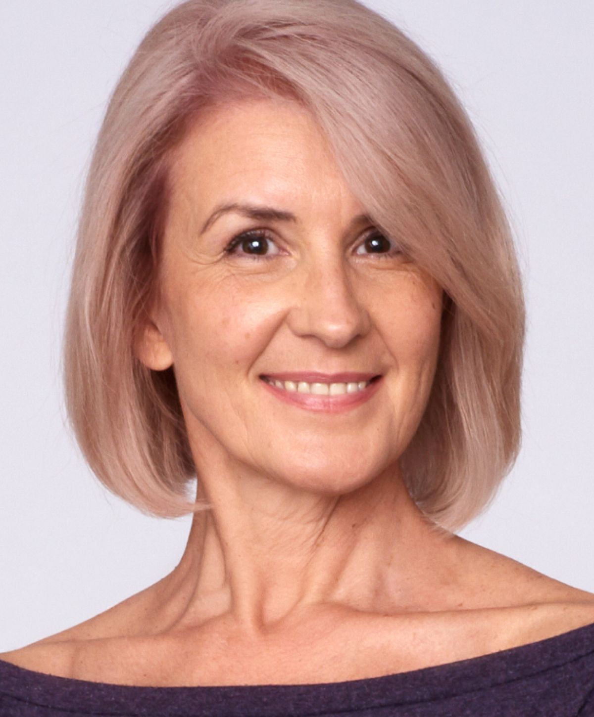 Smiling woman with short, light pink hair.