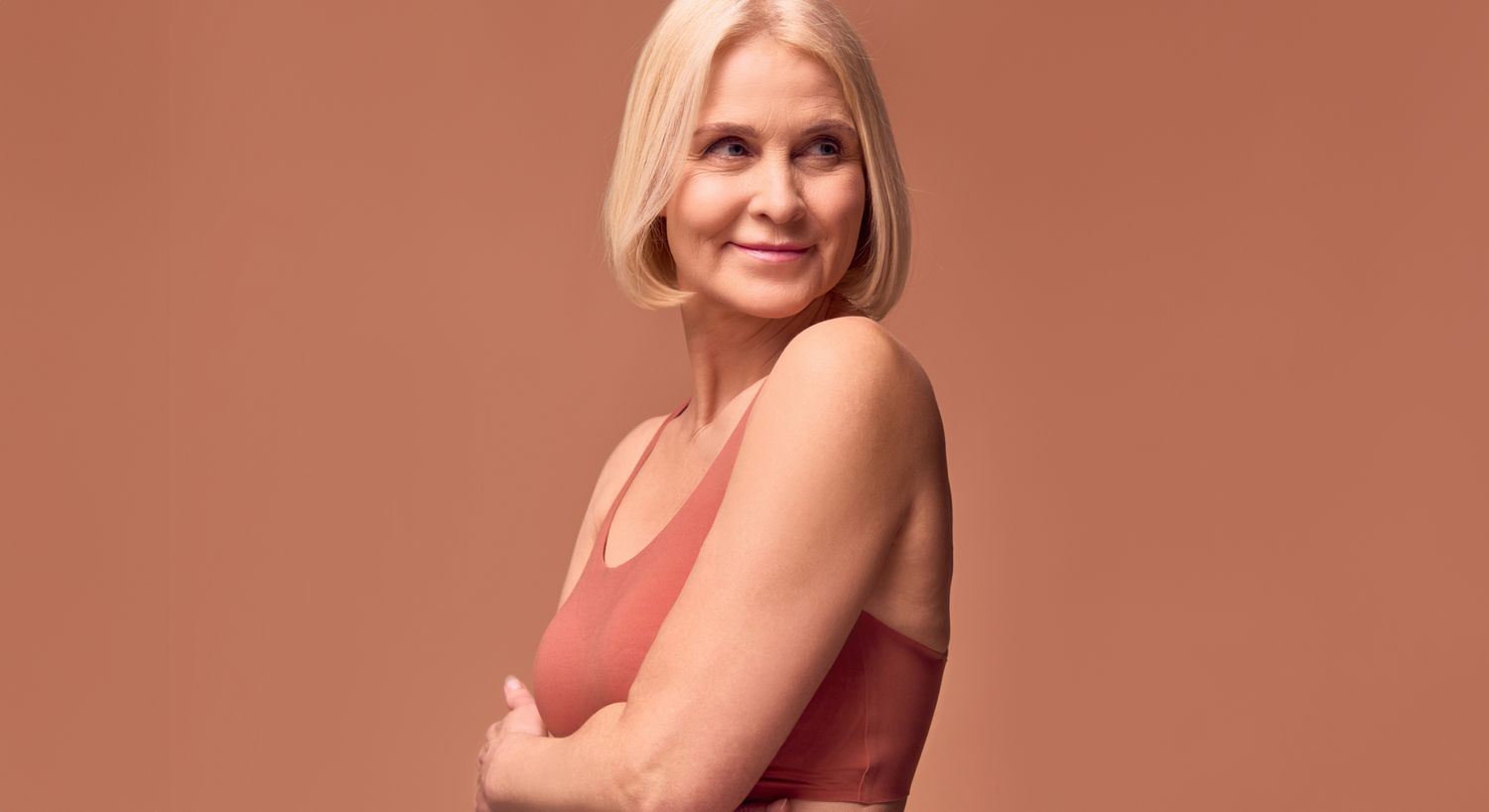 Smiling woman in a sleeveless top against solid background.